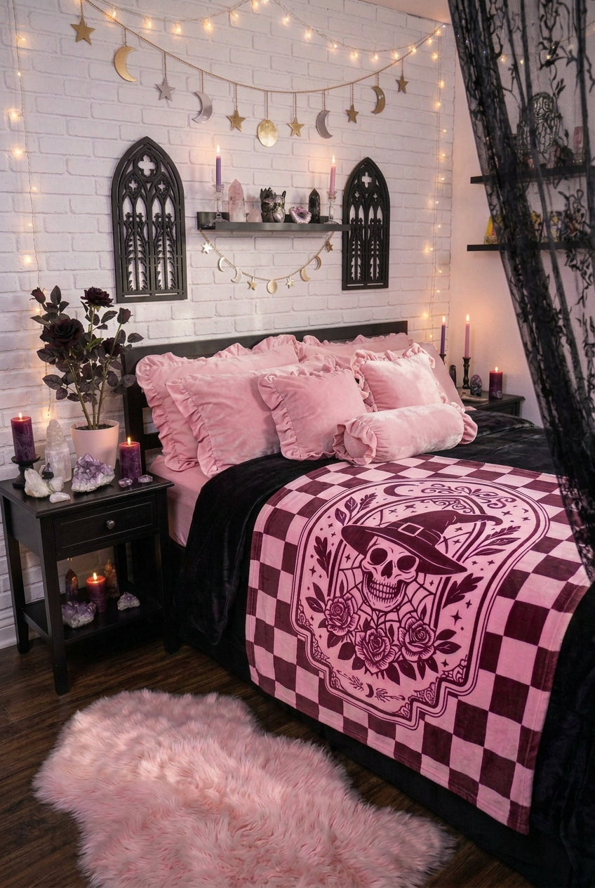 A velveteen throw blanket featuring a dark burgundy and pink checkerboard border and a central graphic of a skull wearing a witch hat with roses, stars, and a crescent moon.