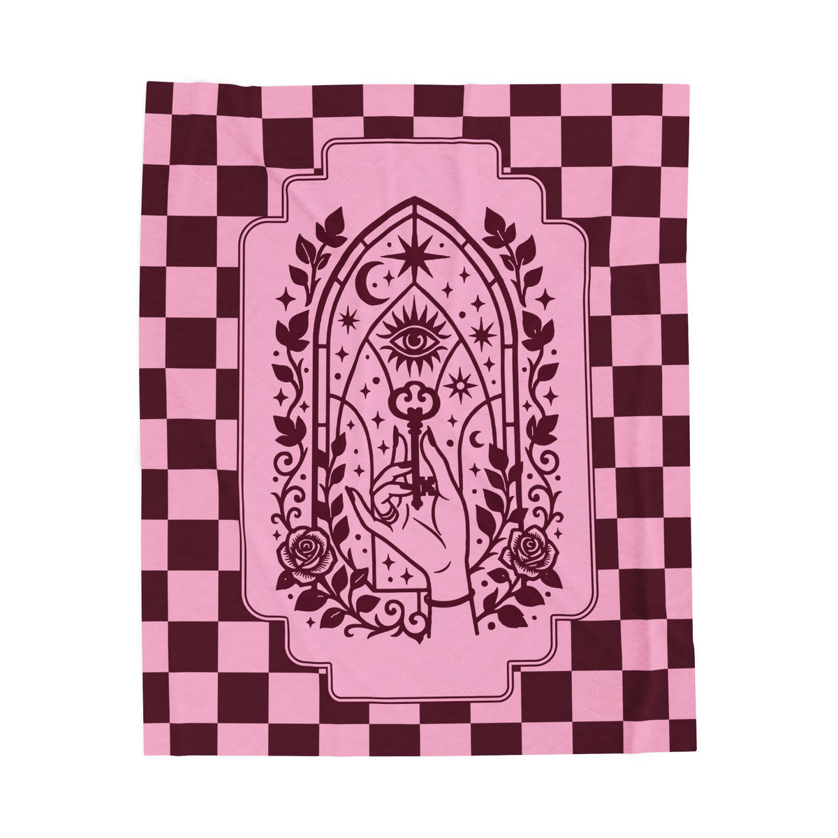 A blanket, featuring a dark burgundy graphic of a hand holding a key in front of an all-seeing eye and rose motif, set against a pink and burgundy checkerboard background.