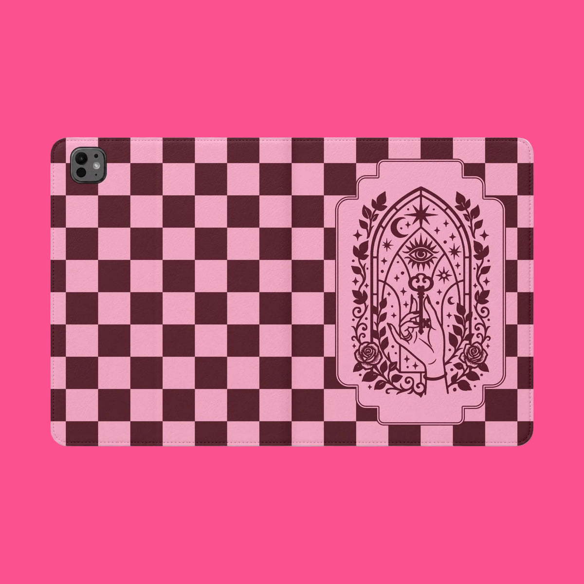 A protective tablet case featuring a pink and dark maroon checkerboard pattern with a central pink gothic arch illustration containing an eye, moon, and rose details.